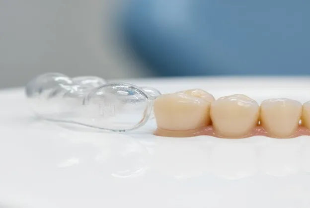 a close-up of a clear night guard resting beside a slightly loose tooth or gum line
