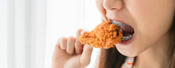 Adult with braces eating safely and smiling