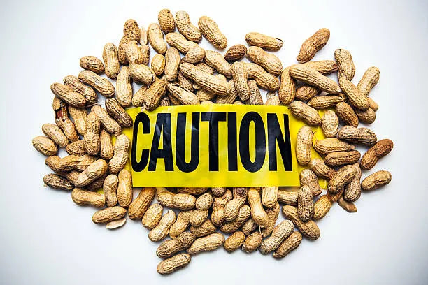 Close-up of a bowl of peanuts with a warning sign overlay