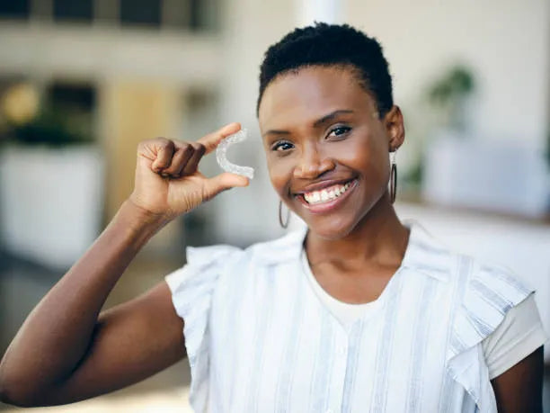 Smiling woman holding a clear retainer