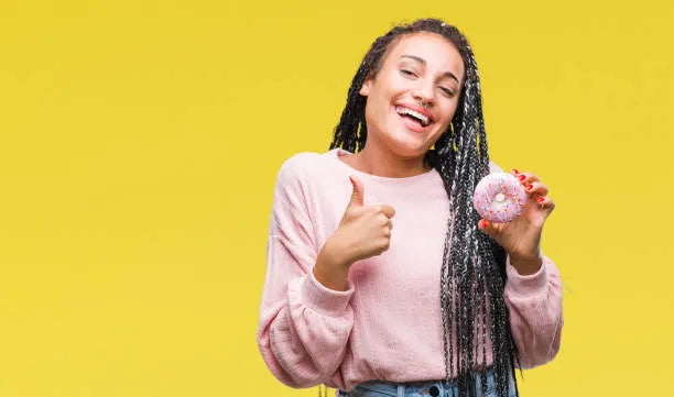 Teen with braces holding a bagel and smiling.