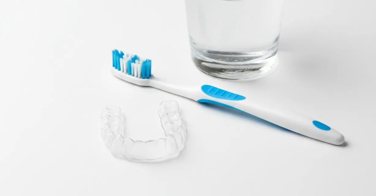 Clean retainer with toothbrush and glass of water – retainer hygiene tips for fresh breath and healthy teeth