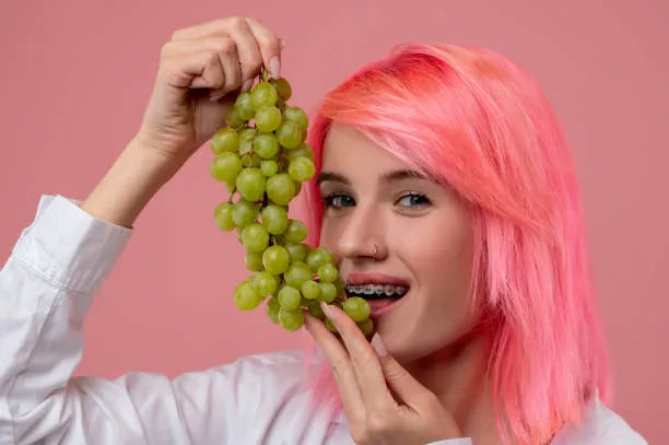 person with braces eating sliced grapes